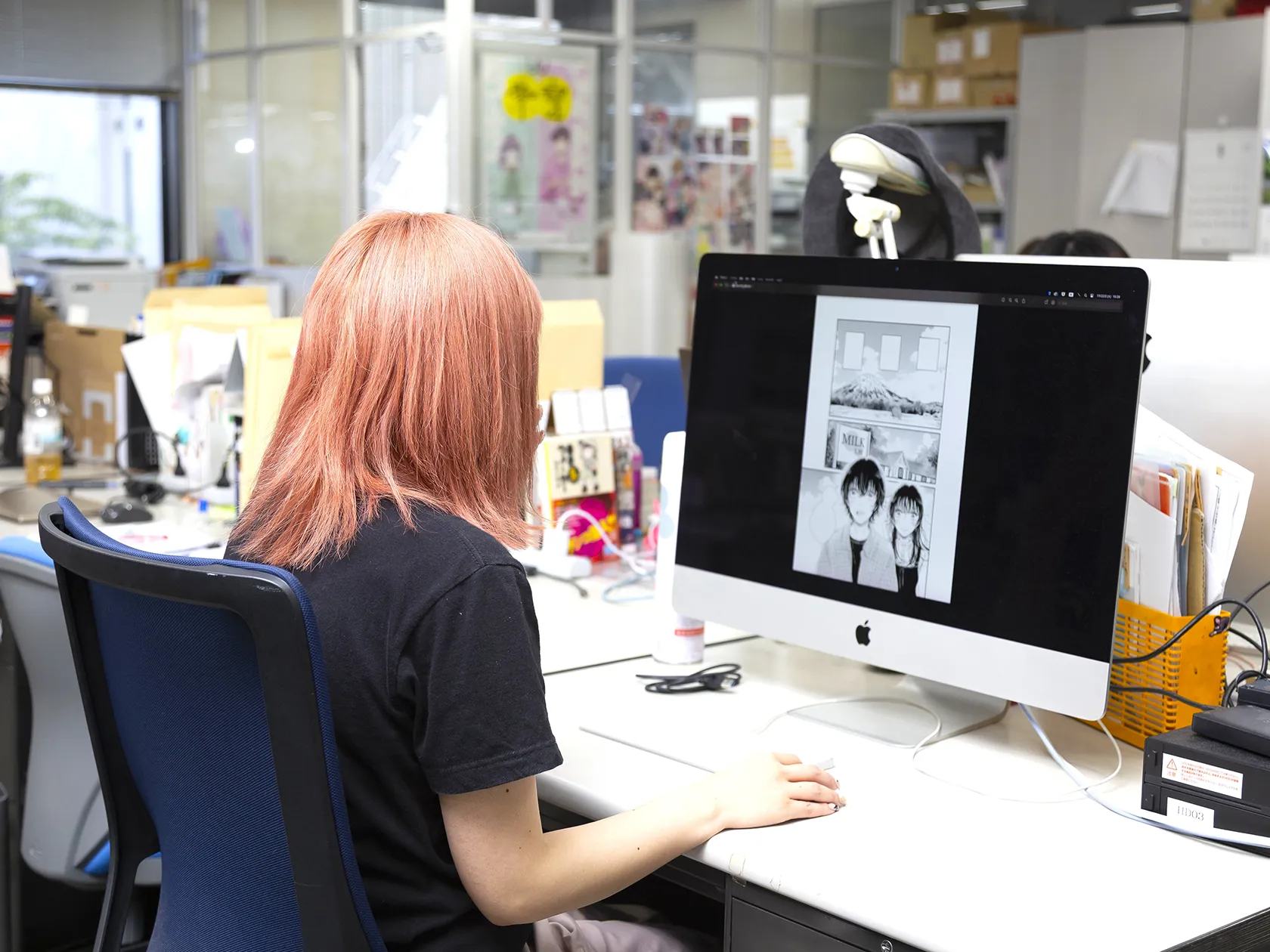 編集部のデスクで、モニターを使ってマンガの編集作業を行っている様子。
